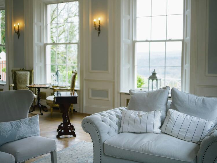 A heritage living room with a hand-knotted teal area rug and a chesterfield sofa