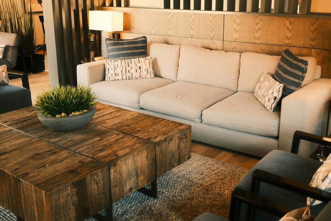 A sunlit modern living room with a beige sectional sofa and a textured area rug — the kind of room Smithwerks cleans